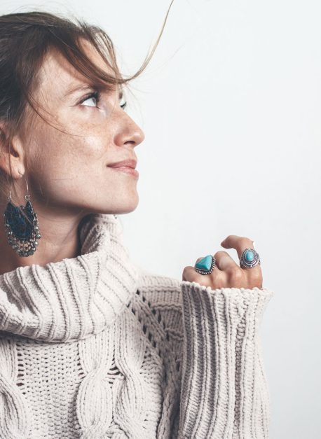 Boho jewelry and woolen sweater on model Boho jewelry on model: ethnic stone rings and earrings. Beautiful woman wearing warm woolen sweater and fashion jewellery. Minimal style and pastel tone.